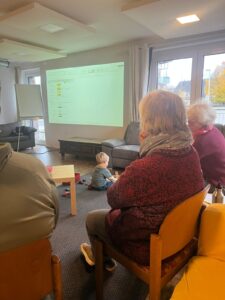 Im Sitzkreis der Gruppe sieht man ein Kind am Boden spielen